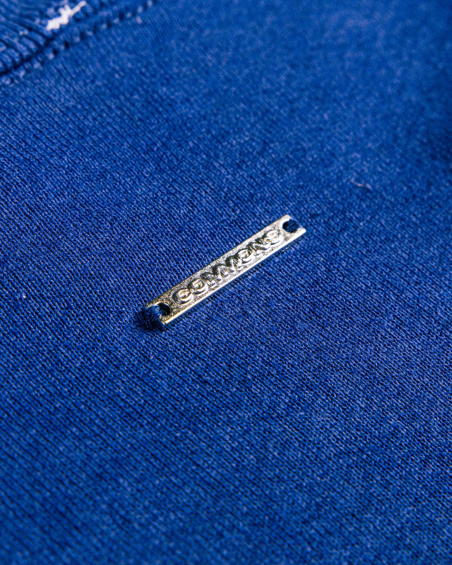 Close-up of royal blue knit fabric with a silver-tone Converse logo plate stitched in place.
