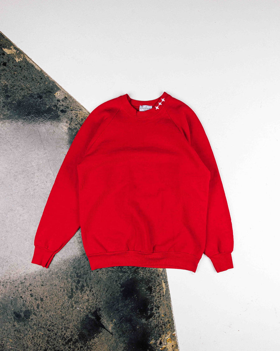 Red crewneck sweatshirt with three white stars at the collar and ribbed cuffs and hem, laid flat on a gray and white floor.