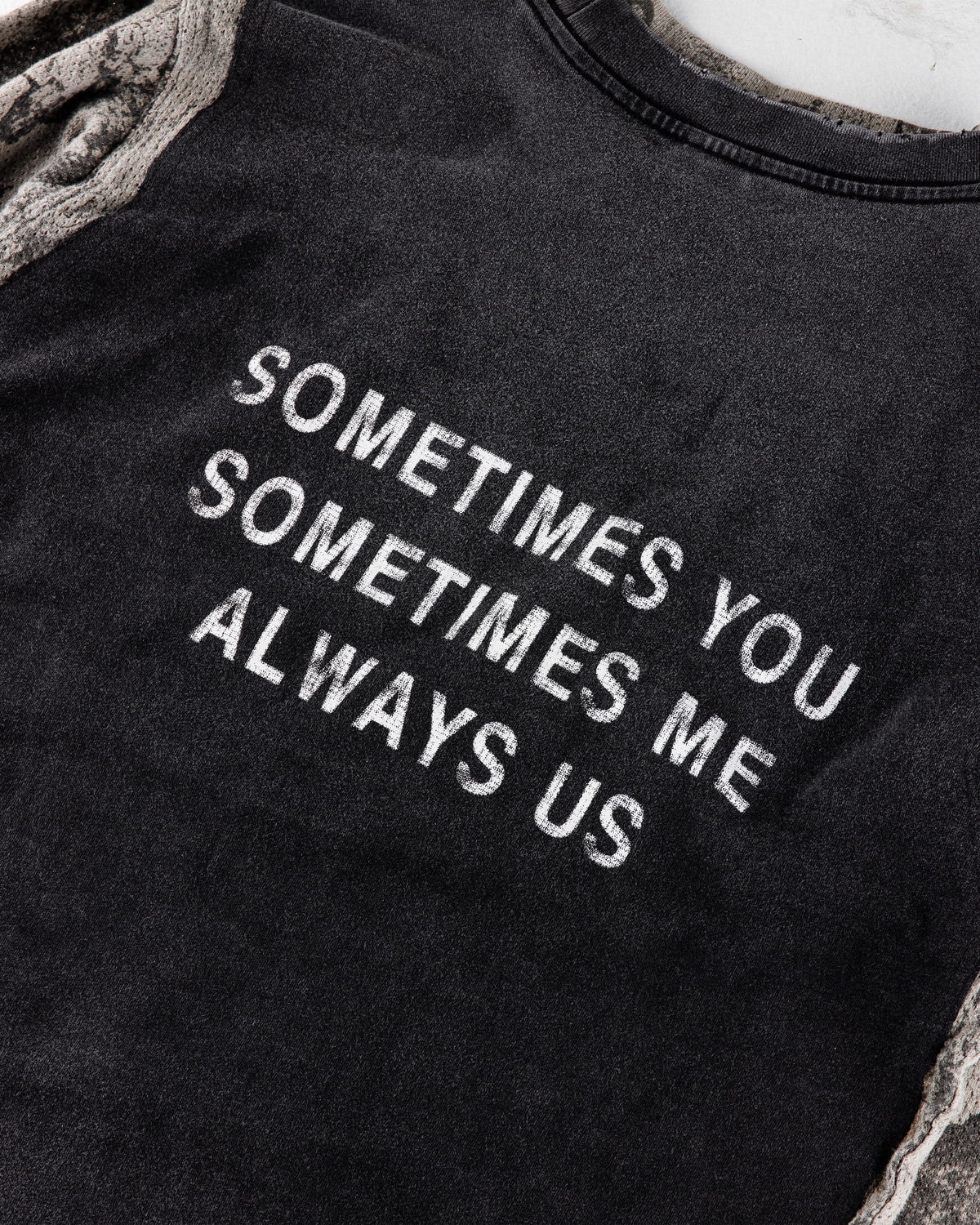 Black crewneck shirt with camouflage sleeves and white text reading Sometimes you, sometimes me, always us.