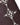 Close-up of brown knit fabric embellished with white pearl-like beads in varied sizes arranged in diamond patterns.