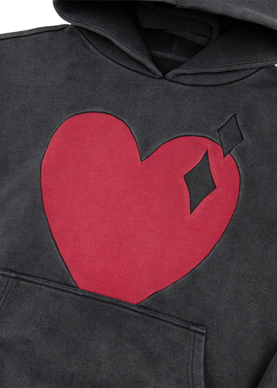 Close-up of a charcoal hoodie with a large red heart, black diamond details, and a kangaroo pocket.