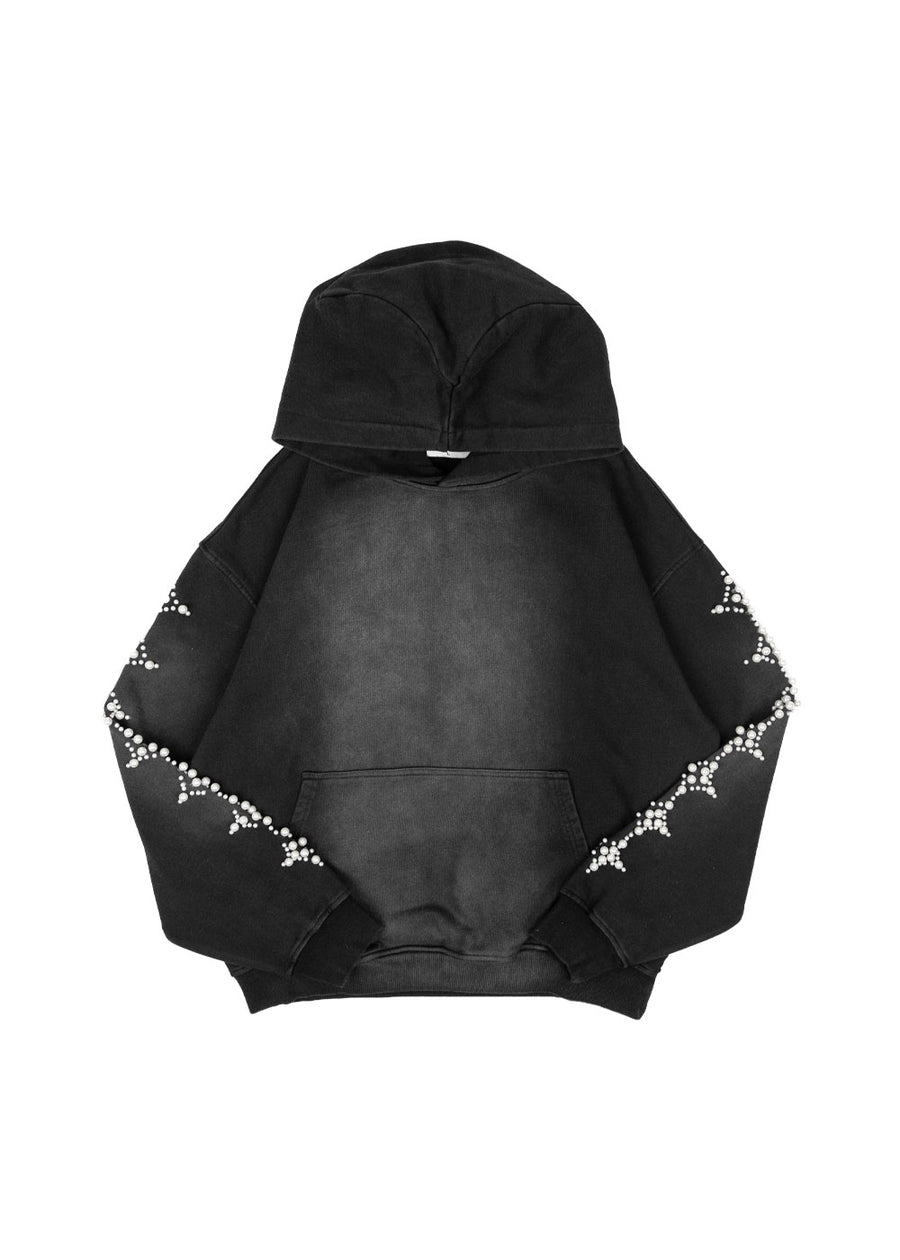 Washed black pullover hoodie with white pearl-like sleeve embellishments and a kangaroo pocket on a white background.