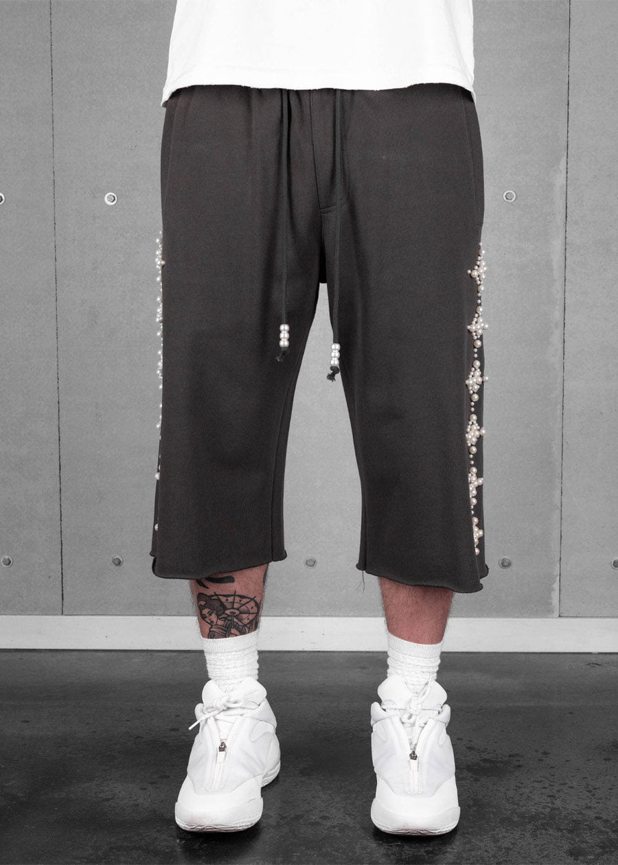Model wears dark gray cropped wide-leg pants with pearl-beaded sides and drawstrings, white socks and white sneakers.