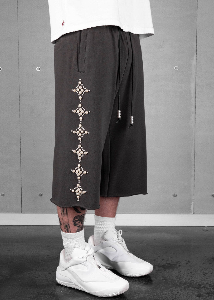 Model wearing dark taupe-grey drawstring shorts with pearl-like diamond embellishments, white socks and white sneakers.