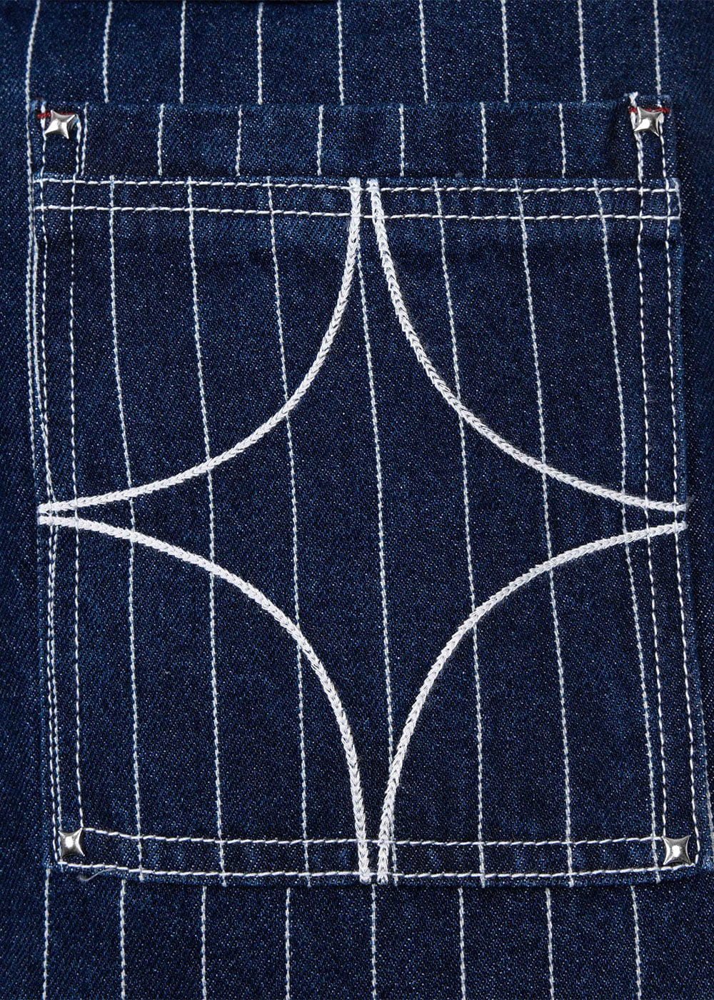 Close-up of a navy pinstriped denim pocket with white curved decorative stitching and silver corner studs.