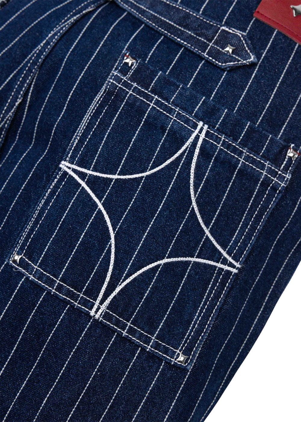Close-up of navy pinstriped denim pants with a back pocket, curved white embroidery, and silver-tone rivets.