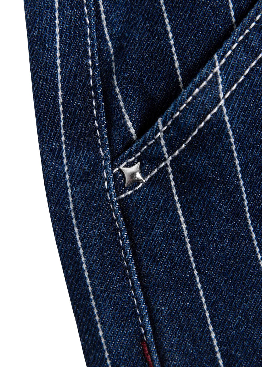 Close-up of a dark blue denim pocket with white pinstripes, contrast stitching, and a silver star-shaped rivet.