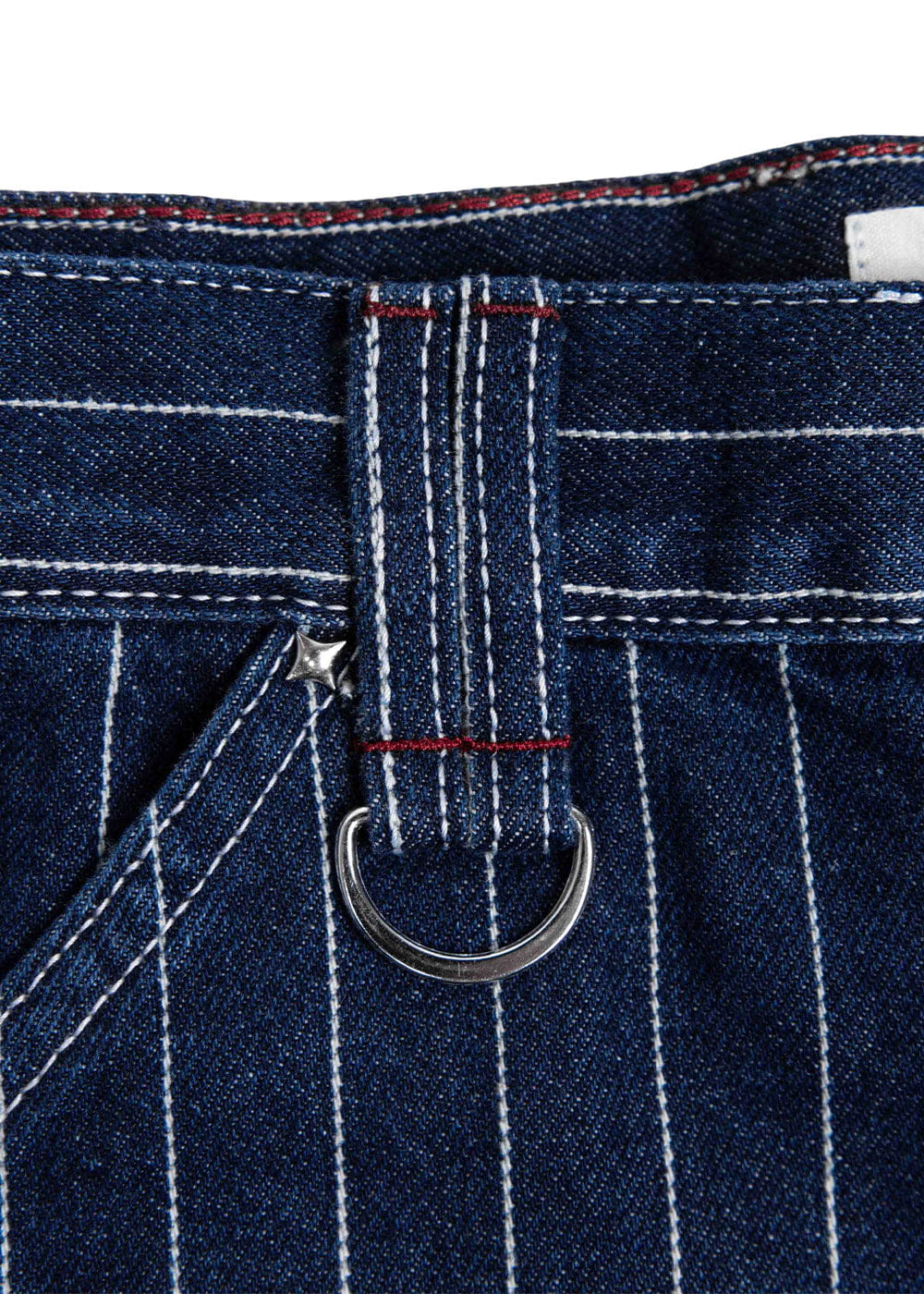 Close-up of dark blue pinstriped denim pants with white stitching, red bar tacks, a metal D-ring, and a star rivet.
