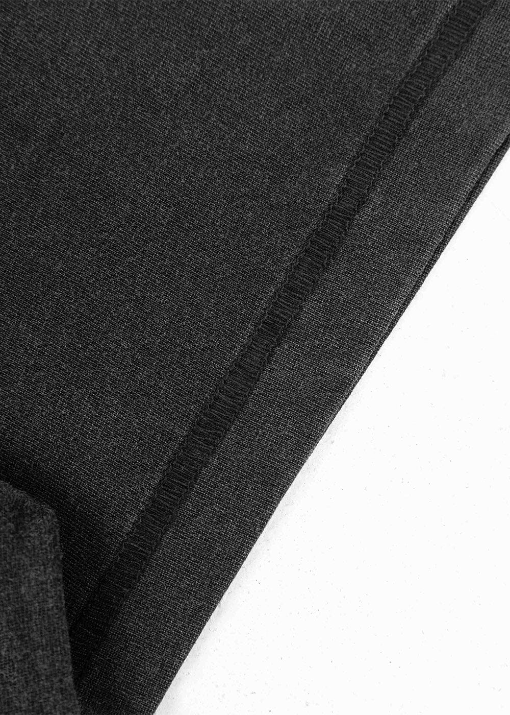 Close-up of black knit fabric with a folded hem and black overlock stitching on a white background.