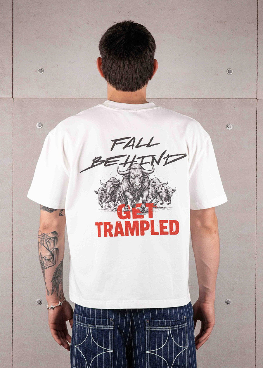 Back view of a person wearing a white T-shirt with black bull graphics and black and red lettering against a concrete wall.