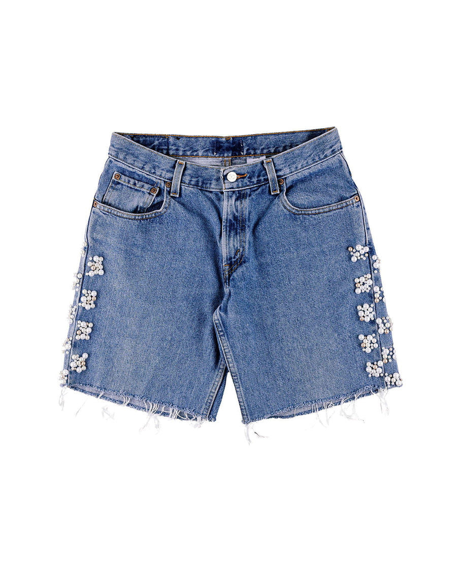 Blue denim shorts with frayed hems, front pockets, and pearl-like floral embellishments along the sides on white.