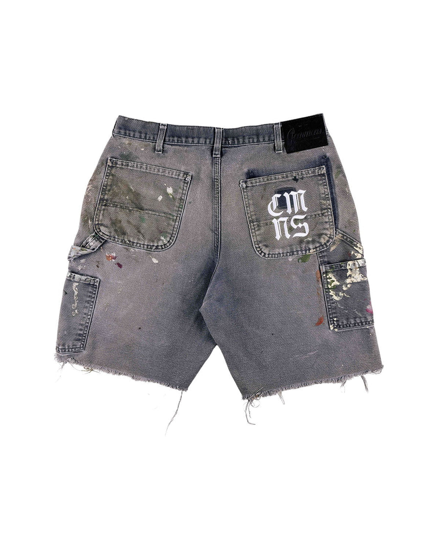 Back view of gray denim shorts with paint splatters, frayed hems, utility pockets, and white lettering on one back pocket.