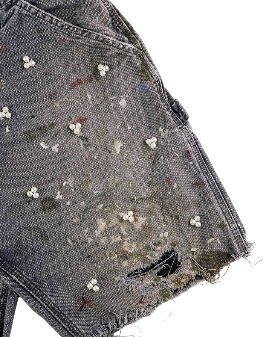 Gray denim shorts with pearl-like bead clusters, multicolored paint splatters, and a distressed frayed hem.