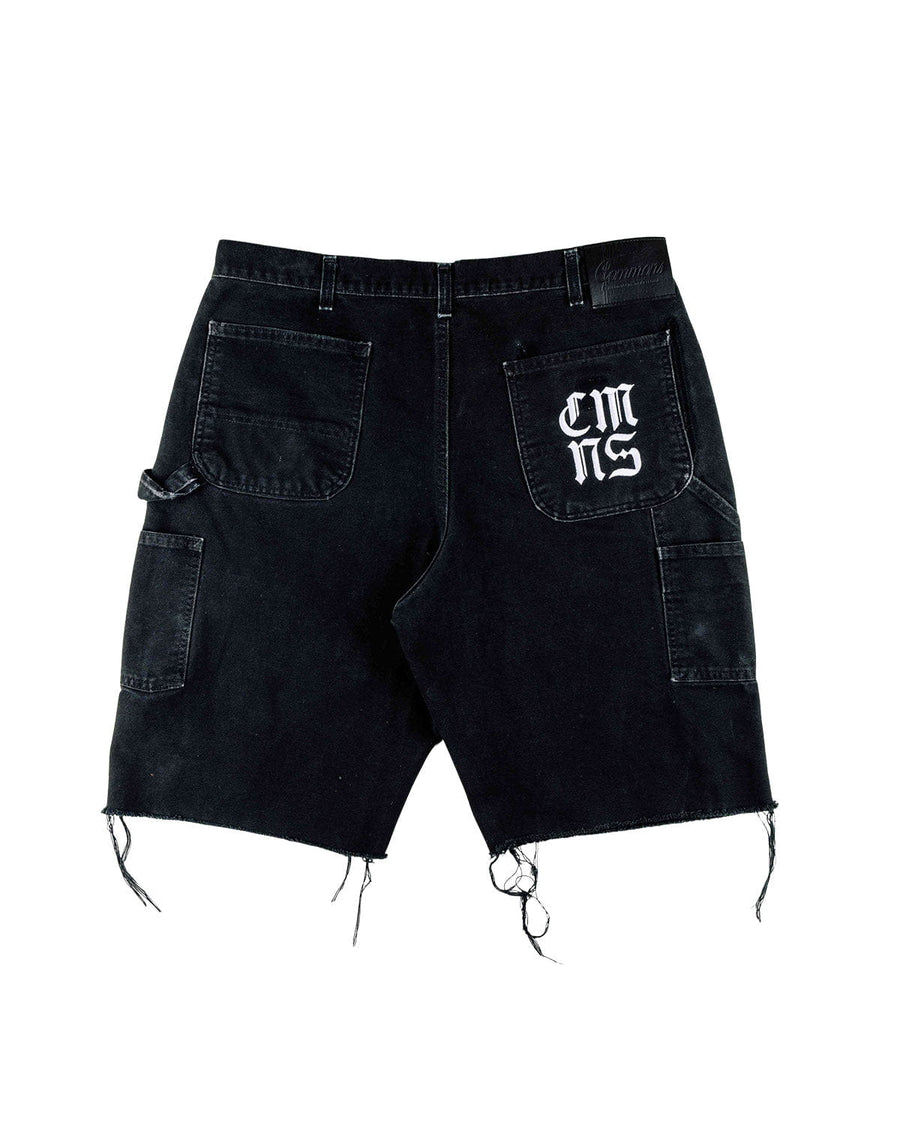 Back view of black denim carpenter shorts with frayed hems, utility pockets, hammer loop, and white back-pocket lettering.