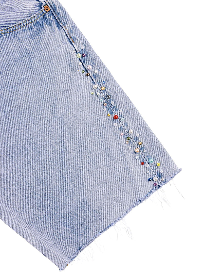 Light blue denim skirt with multicolored pearl-like beads along the side seam and a frayed hem on a white background.