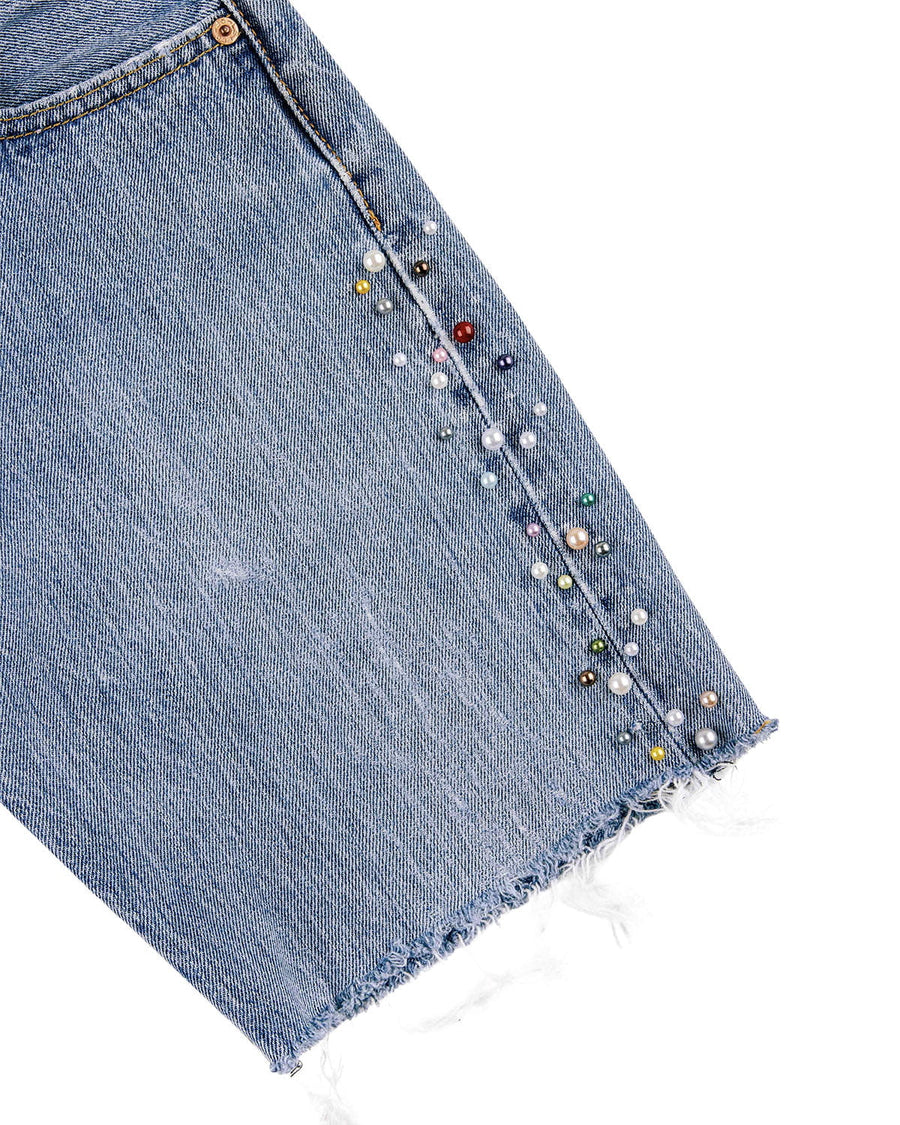 Light blue denim shorts with multicolored pearl-like beads along the side seam and a frayed hem on a white background.