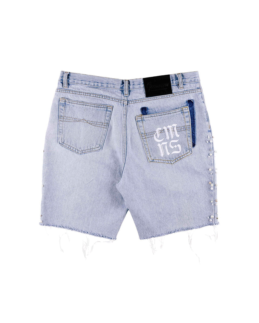 Back view of light blue denim shorts with frayed hems, pearl-like side beads, and white lettering on one back pocket.
