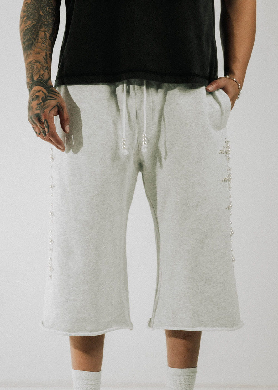 Model wears light gray wide-leg knit shorts with pearl-trimmed sides, beaded drawstrings, and raw hems.